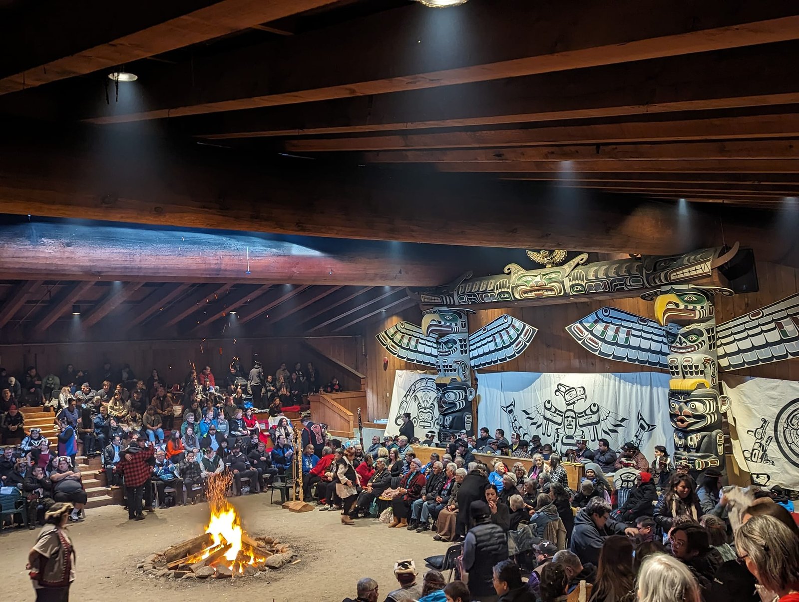 Interior view of an Indigenous Big House, revealing the rich cultural tapestry within. Traditional artwork, ceremonial space, and symbolic elements create a profound sense of heritage and community within the sacred walls.